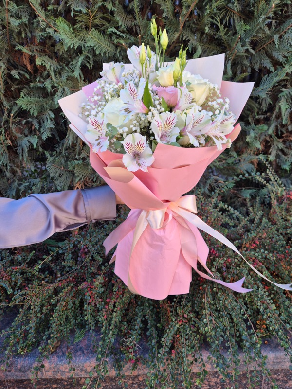 Buchet pastel ambalat în hârtie roz, cu trandafiri, lisianthus și floarea-miresei