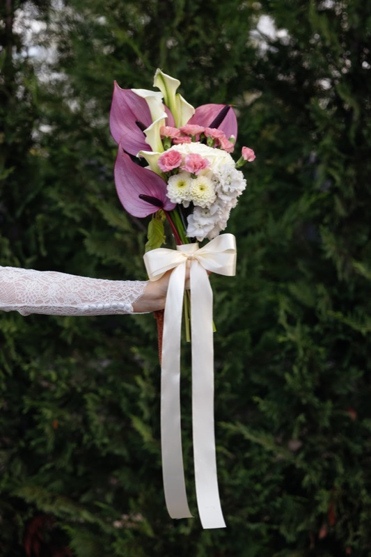 Aranjament floral în roz, mov și alb, legat cu panglici pentru ceremonie